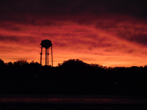 sky lit orange by sunset, water tower in silhouette