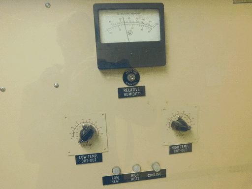 Close up of top half of the second control panel with a "% RELATIVE HUMIDITY" meter, beneath which is a toggle switch controlling which scale (0-100 or 0-50%) it uses, two chickenhead knobs on square base plates labeled "LOW TEMP. CUT OUT" and "HIGH TEMP. CUT-OUT," and three white lights labeled "LOW HEAT," "HIGH HEAT," and "COOLING."