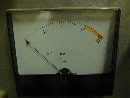 Close-up of one of the Simpson KV meters. It's very dusty on top, of course. I already described the basics. The needle pointer's pointer end has a bulbous base and thin tip like an exaggerated raindrop. Between 15 and 20 on the scale over the tick marks there's a sloppily applied arc of amber dye. There's an even sloppier blob of red dye over the 19 tick mark, and of orange dye between 19.5 and 20.